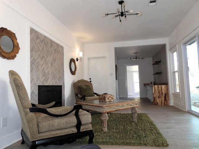 living room featuring a fireplace, hardwood / wood-style floors, a healthy amount of sunlight, and ceiling fan with notable chandelier