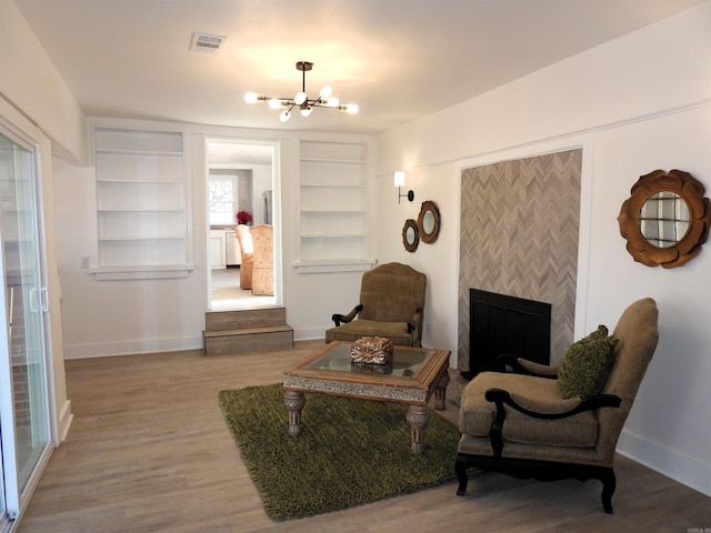 living area featuring hardwood / wood-style flooring, a notable chandelier, and built in features