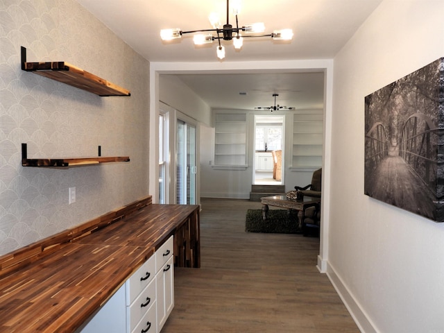 corridor with dark wood-type flooring and an inviting chandelier