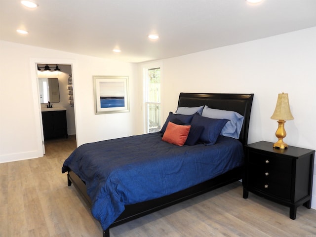 bedroom with light hardwood / wood-style floors and connected bathroom