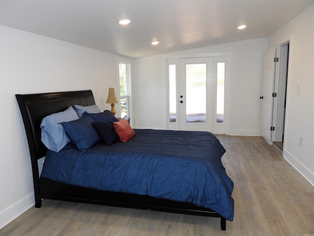 bedroom featuring hardwood / wood-style flooring, access to exterior, and vaulted ceiling