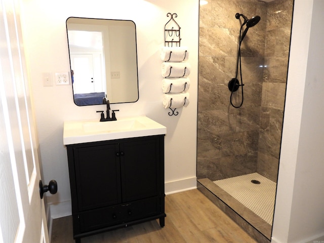 bathroom featuring hardwood / wood-style flooring, vanity, and a tile shower