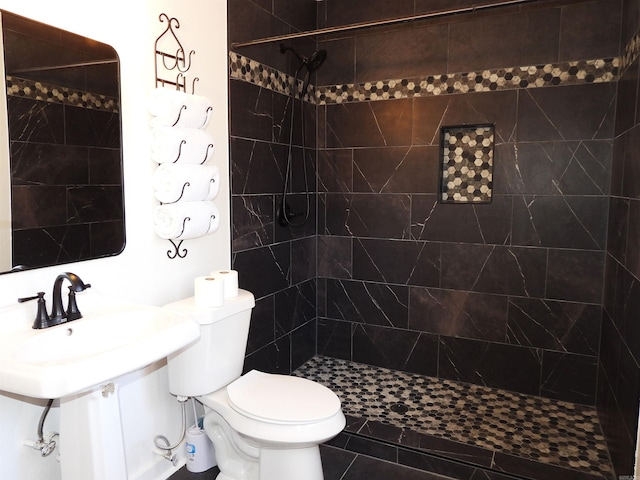 bathroom featuring a tile shower, tile patterned flooring, and toilet