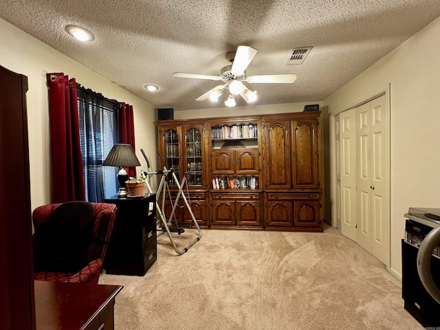 carpeted office space with ceiling fan and a textured ceiling