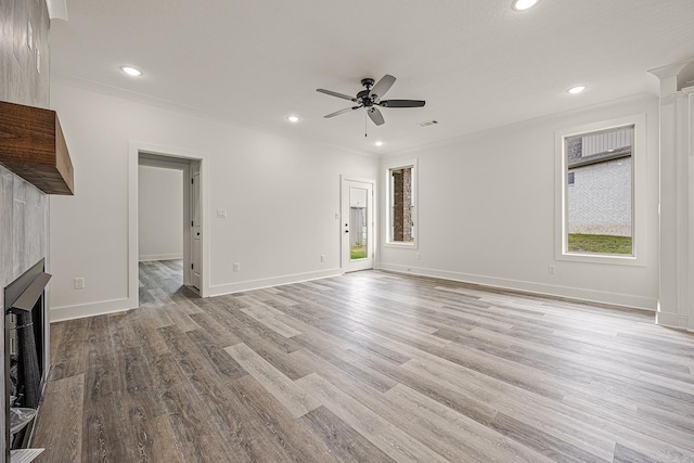 unfurnished living room featuring ceiling fan, light wood-type flooring, crown molding, and a tile fireplace