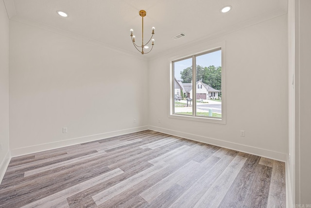 empty room featuring ornamental molding, light wood-type flooring, and a notable chandelier