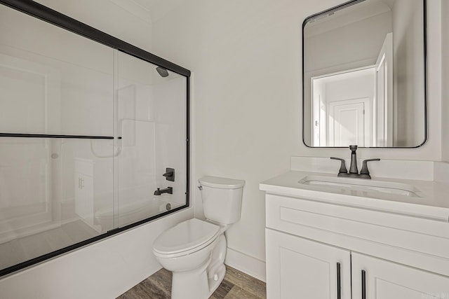 full bathroom featuring hardwood / wood-style floors, vanity, toilet, and bath / shower combo with glass door