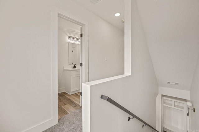 stairs featuring hardwood / wood-style floors, lofted ceiling, and sink