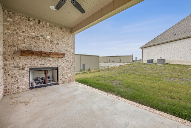 view of yard with central AC, ceiling fan, a patio, and exterior fireplace