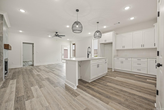 kitchen with white cabinets, a center island with sink, ceiling fan, and sink