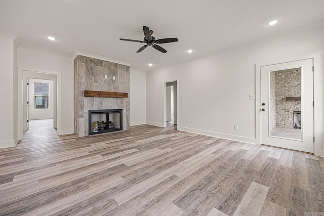 unfurnished living room with ceiling fan, ornamental molding, a fireplace, and light hardwood / wood-style flooring