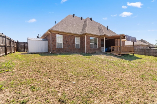 rear view of house featuring a deck, a storage unit, and a lawn