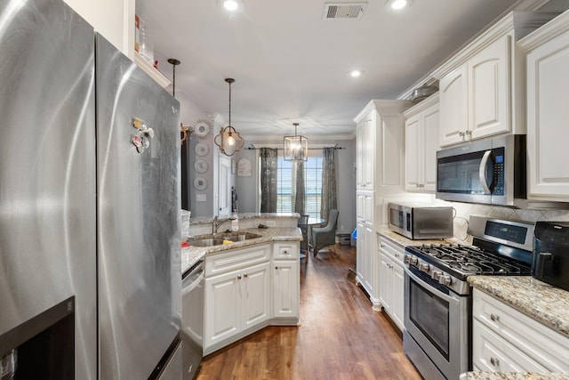 kitchen with dark hardwood / wood-style flooring, stainless steel appliances, crown molding, pendant lighting, and white cabinetry