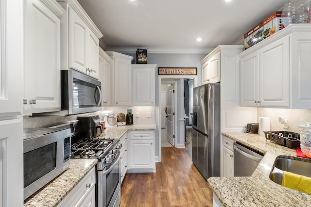 kitchen featuring white cabinets, stainless steel appliances, dark hardwood / wood-style floors, and crown molding