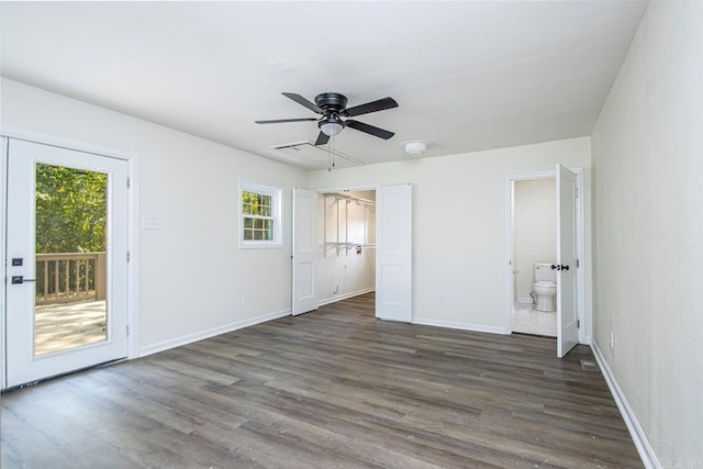 unfurnished bedroom featuring ensuite bathroom, ceiling fan, dark hardwood / wood-style flooring, and multiple windows