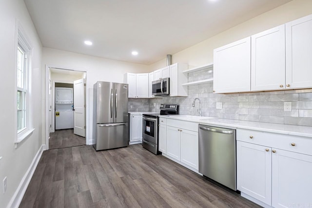 kitchen with appliances with stainless steel finishes, tasteful backsplash, sink, wood-type flooring, and white cabinets