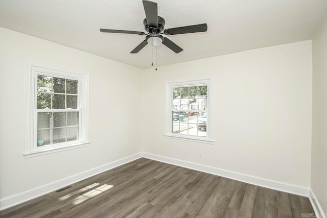 empty room featuring a wealth of natural light, ceiling fan, and dark hardwood / wood-style floors