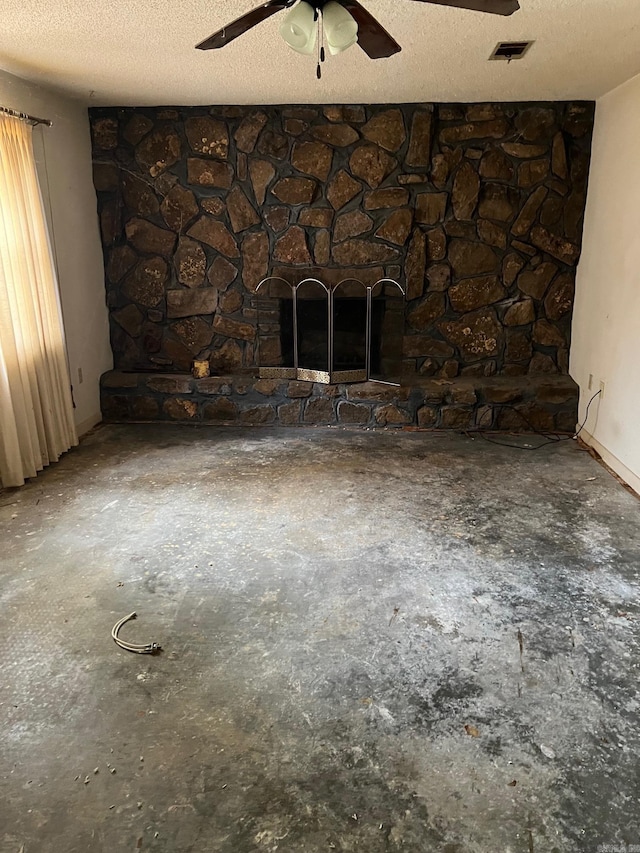 unfurnished living room with a textured ceiling and a stone fireplace