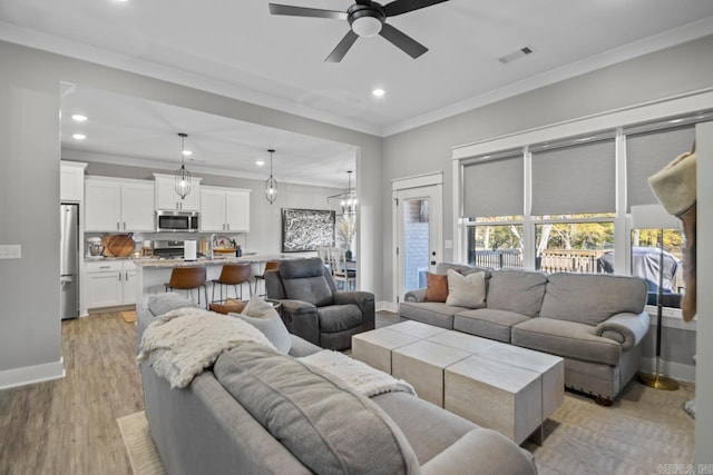 living room with ceiling fan, sink, light wood-type flooring, and ornamental molding