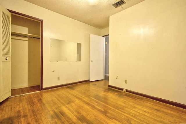 unfurnished bedroom featuring wood-type flooring, a textured ceiling, and a closet