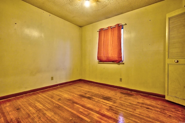 empty room with wood-type flooring and a textured ceiling