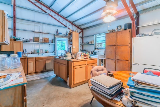 kitchen featuring concrete flooring, white appliances, and vaulted ceiling