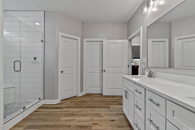 bathroom with vanity, wood-type flooring, a textured ceiling, and walk in shower