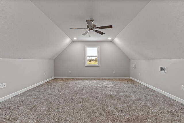 additional living space featuring ceiling fan, lofted ceiling, carpet floors, and a textured ceiling