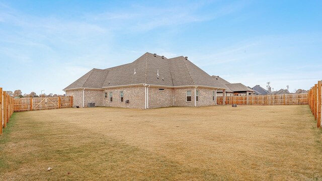 rear view of house featuring central AC and a lawn