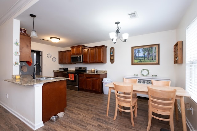 kitchen with dark wood-type flooring, sink, appliances with stainless steel finishes, decorative light fixtures, and kitchen peninsula