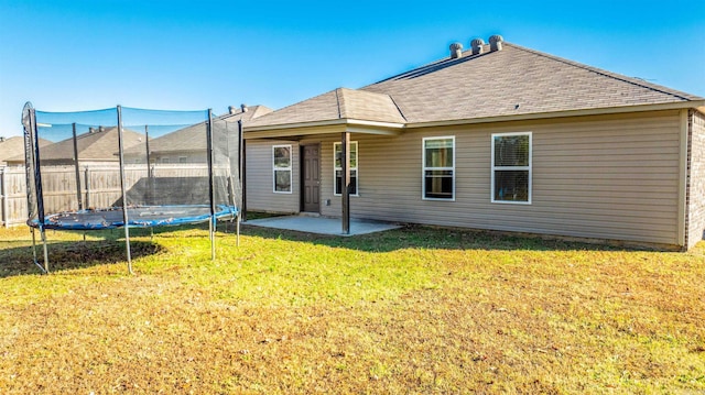 rear view of house with a lawn, a patio area, and a trampoline