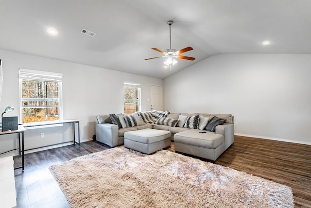 living room with a wealth of natural light, ceiling fan, dark wood-type flooring, and vaulted ceiling