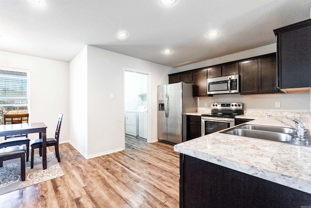 kitchen featuring dark brown cabinetry, sink, stainless steel appliances, light hardwood / wood-style flooring, and washer and clothes dryer