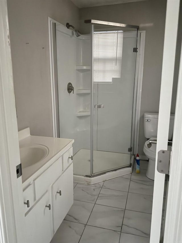 bathroom with a shower with door, vanity, and toilet