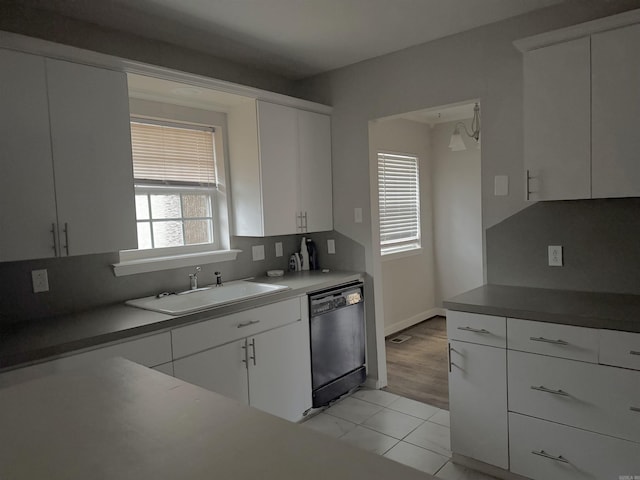 kitchen featuring white cabinetry, sink, light hardwood / wood-style flooring, and black dishwasher