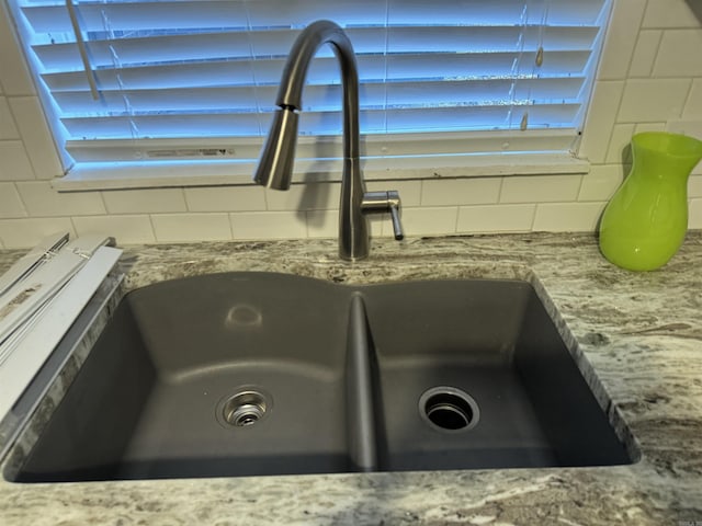 details featuring backsplash, sink, and stone counters