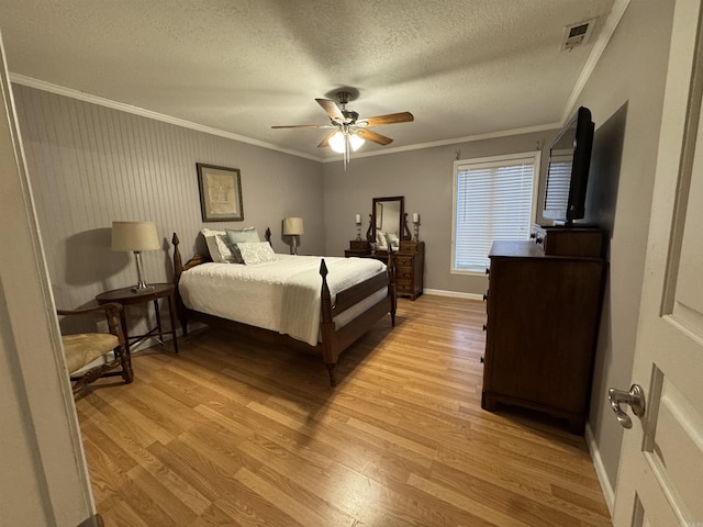 bedroom with a textured ceiling, light wood-type flooring, ceiling fan, and ornamental molding