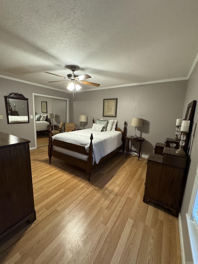 bedroom featuring a textured ceiling, light wood-type flooring, ceiling fan, and ornamental molding