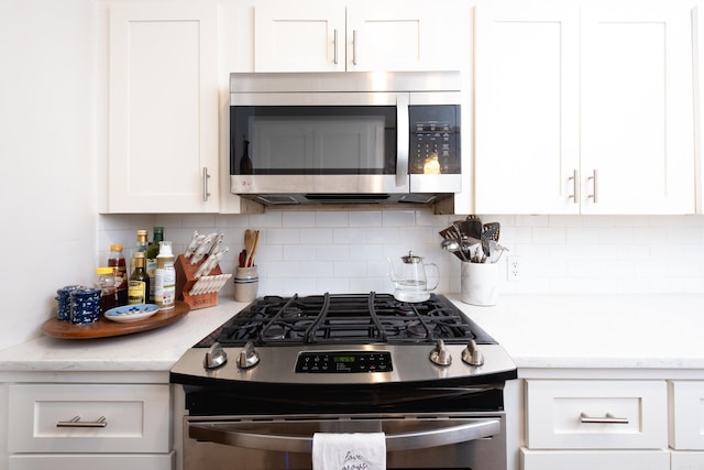 kitchen with backsplash, white cabinetry, light stone countertops, and appliances with stainless steel finishes