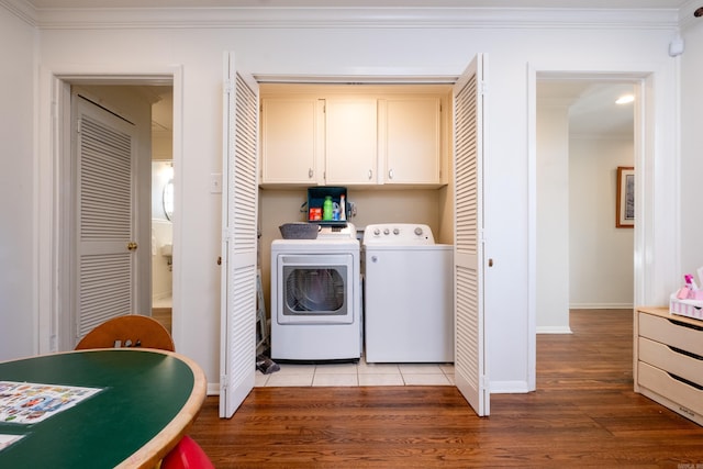 washroom with washing machine and dryer, cabinets, crown molding, and light hardwood / wood-style floors