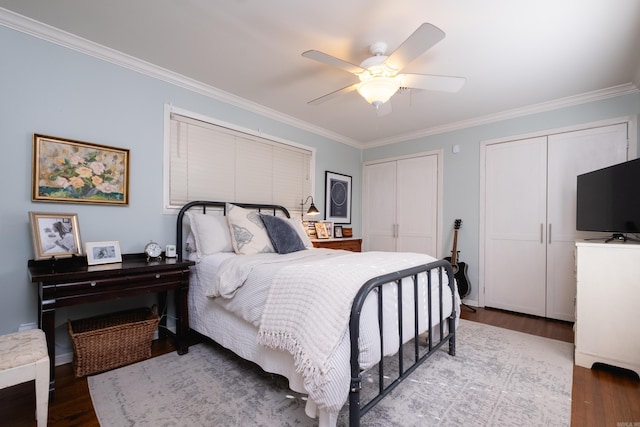 bedroom featuring two closets, light hardwood / wood-style flooring, ceiling fan, and ornamental molding