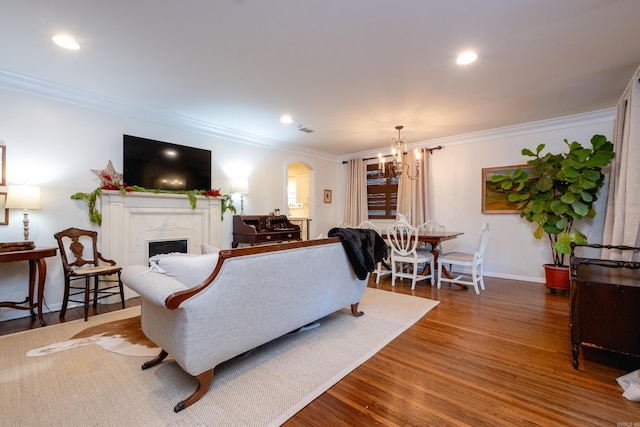 living room featuring wood-type flooring, an inviting chandelier, and ornamental molding