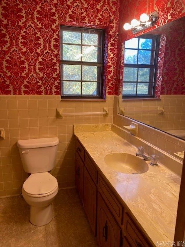 bathroom featuring tile patterned flooring, vanity, toilet, and tile walls