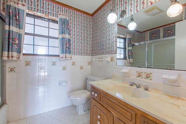 bathroom with tile patterned floors, vanity, tile walls, toilet, and a shower with shower door