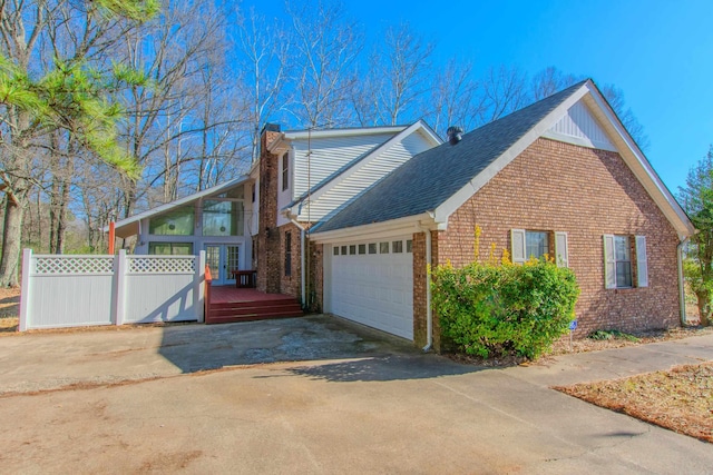 view of side of property featuring a sunroom, a garage, and a deck