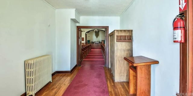 hallway with crown molding, radiator heating unit, and dark wood-type flooring