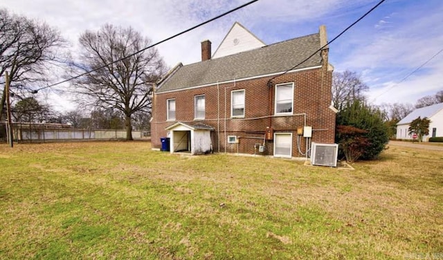 rear view of house featuring a lawn and cooling unit