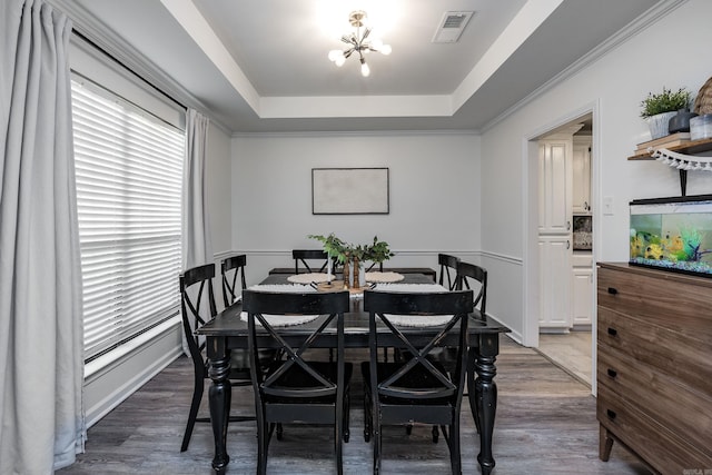 dining space featuring a raised ceiling, a chandelier, and wood-type flooring