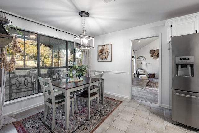 dining space with an inviting chandelier, light wood-type flooring, and vaulted ceiling