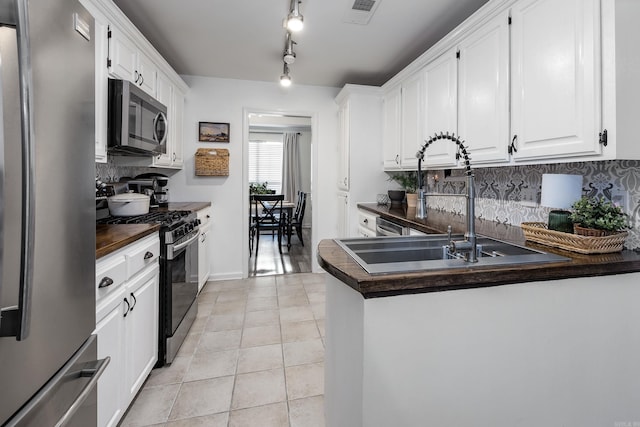 kitchen with decorative backsplash, white cabinetry, stainless steel appliances, and light tile patterned floors